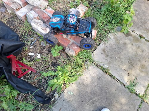 Reviewer's RC rock crawler buggy with black and blue Unchained stickers on its body, posed on a pile of bricks outdoors.