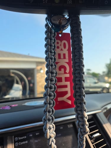 Reviewer's red 80Eighty air freshener hanging from a car's rearview mirror.