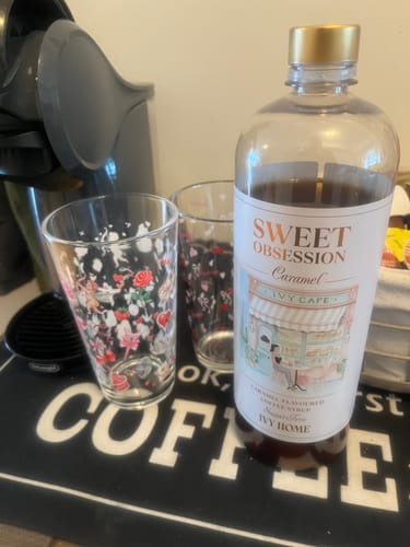 Reviewer's sugar-free Sweet Obsession Caramel Coffee Syrup on a coffee mat with glasses.