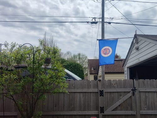 Customer's old style State of Minnesota Flag hanging from a pole in a backyard.