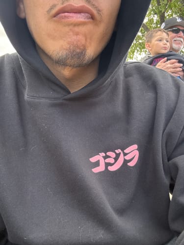 Reviewer wearing a black hoodie with pink Japanese text, an item from their mystery box.