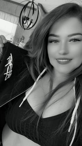 Reviewer in a close-up photo, wearing the unzipped black 80Eighty Signature Zip Hoodie and holding it up to show the embroidery.