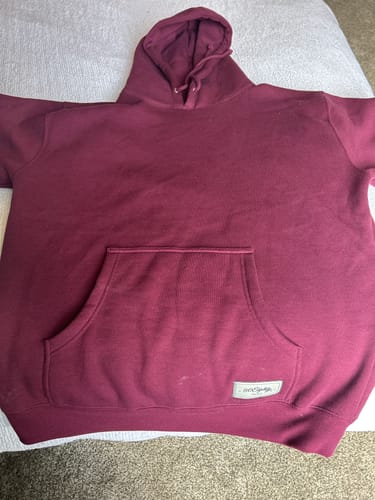 Reviewer's Crimson Heavyweight Hoodie laid out flat, showing its thick material and front pouch.