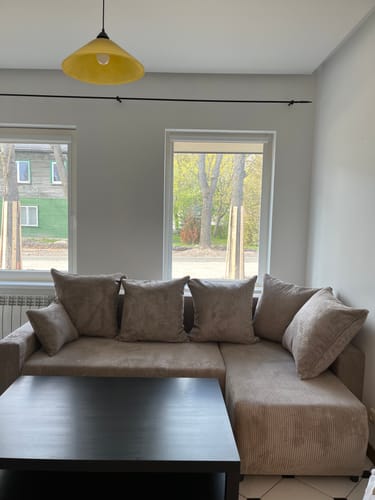 Kliento ruda kampinė sofa su pagalvėlėmis, pastatyta svetainėje.