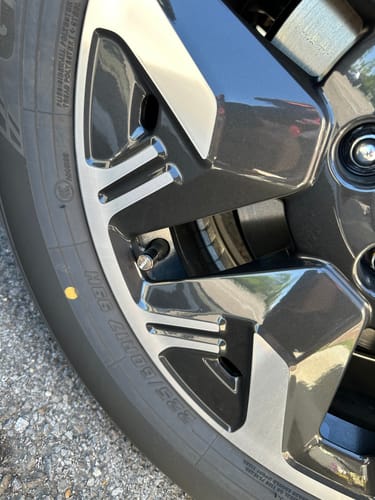 A customer's silver 80Eighty Valve Stem Cap installed on a two-tone car wheel.