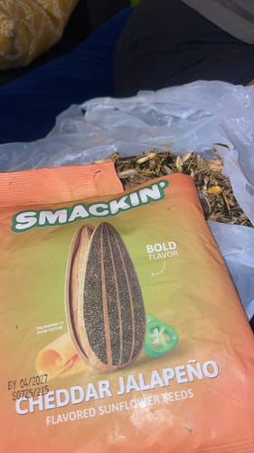 Customer's open bag of Cheddar Jalapeño sunflower seeds with a pile of shells nearby.
