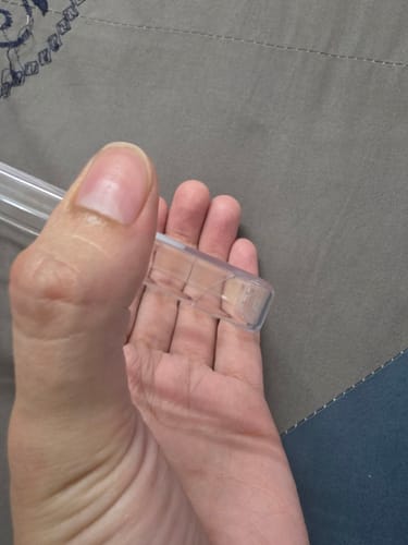 Close-up of a reviewer's hand holding the clear Samsung case, showing two small cracks on the corner.