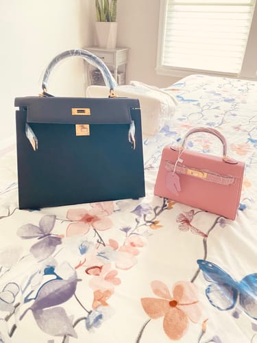 Customer's large black and small pink Kally Leather Bags sitting on a floral bedspread.