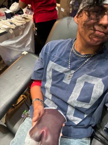 Reviewer donating blood while wearing a silver chain necklace and a link bracelet.