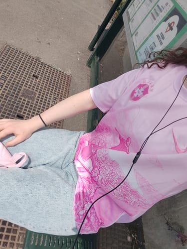 Cliente assise portant son Maillot Mystère, un maillot rose avec un motif graphique.
