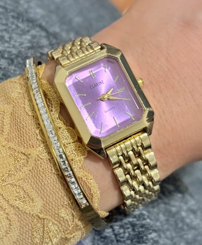 Customer wearing the gold CLAIRE DE MAINS watch with a purple rectangular face and a matching gold band.