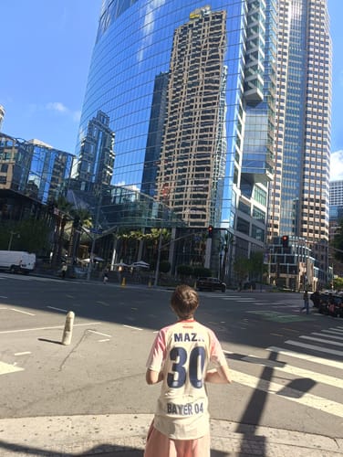 Client vu de dos portant le maillot rose spécial joueur Leverkusen dans un décor urbain.