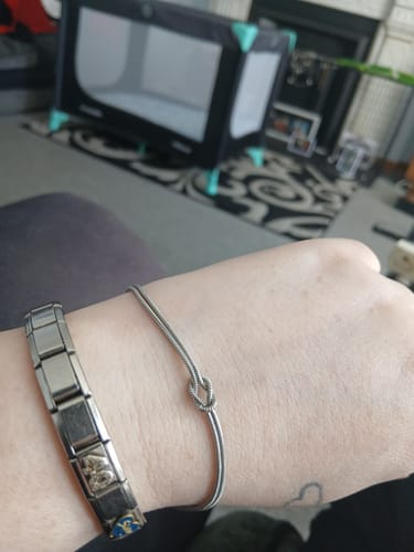 Customer wearing the simple Forever Knot Bracelet on their wrist next to another silver bracelet.