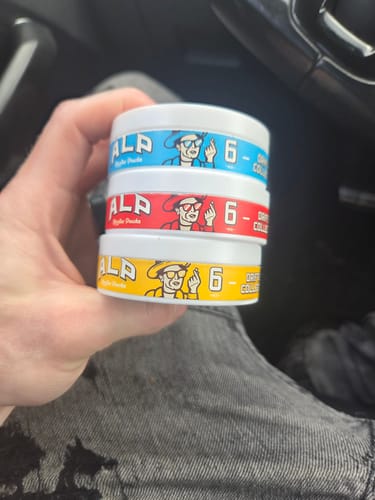 Customer holding a stack of three colorful containers of Drifters Nicotine Pouches.