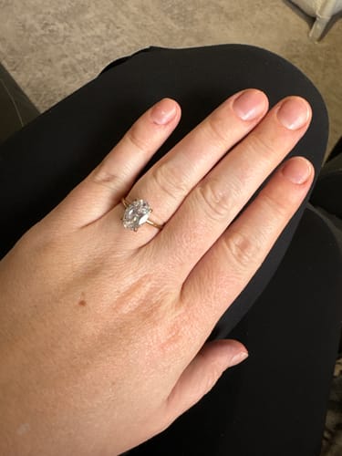 Reviewer's hand wearing the Aura Ring with a large oval stone and a gold band.