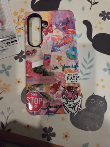 Customer's colorful Happy Place phone case with a collage design shown on a floral surface.