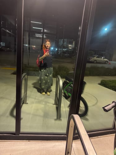 Reviewer wearing the casual dotted low crotch jumpsuit, seen in a window reflection at night.