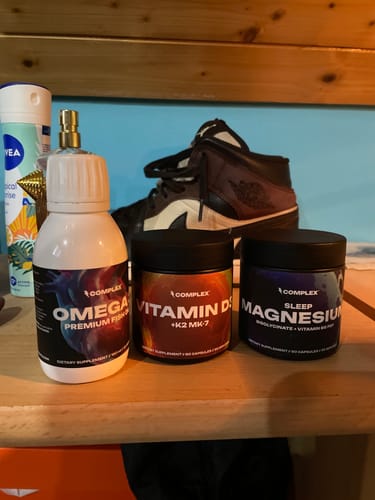 Reviewer's lineup of several Complex brand supplement bottles sitting on a wooden shelf.