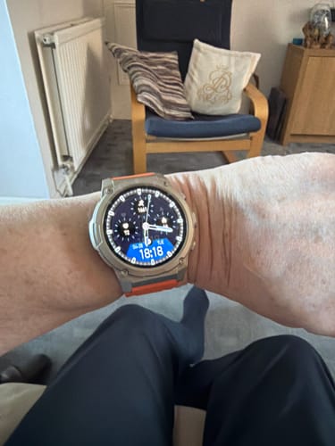 Customer wearing a smartwatch with a silver case and an orange band on their wrist.