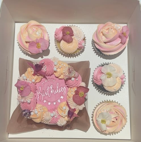 Customer's birthday cake and cupcakes elegantly decorated with FUCHSIA edible flowers in a white box.