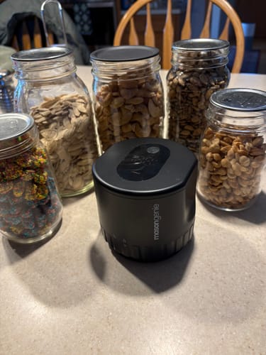 Customer's black Mason Genie Vacuum Sealer on a counter with sealed jars of candy and nuts.