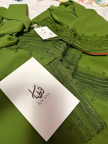 Customer's green Caftan Nazeera with intricate embroidery laid flat with its matching belt.