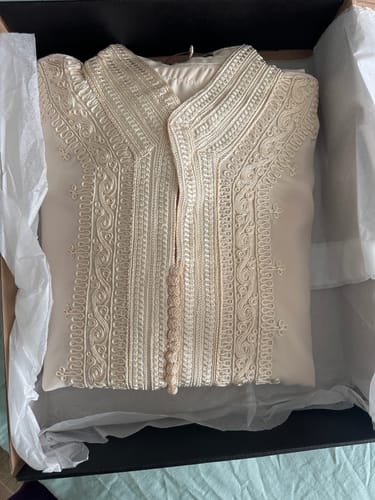 Customer's cream Caftan Nazeera with detailed embroidery, shown folded in its box.