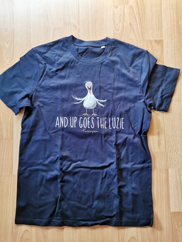 Rezensent zeigt das dunkelblaue Premium Bio-T-Shirt 'And up goes the Luzie' flach liegend auf einem Holzboden.