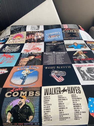 Customer's Project Repat T-Shirt Quilt made from various country music concert t-shirts, spread out on a bed.
