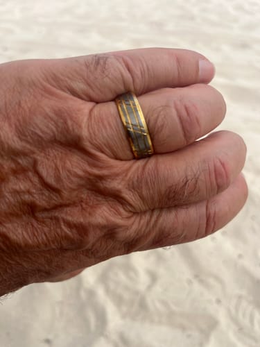 Customer's hand wearing the Bravado ring, showing its brushed silver and gold-accented design.