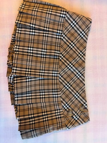 Customer's Girly Plaid Pleated Mini Skirt in khaki, laid flat to show its fabric and pleated design.