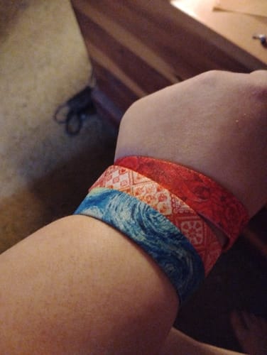 Customer's wrist with three colorful, patterned bracelets stacked together.