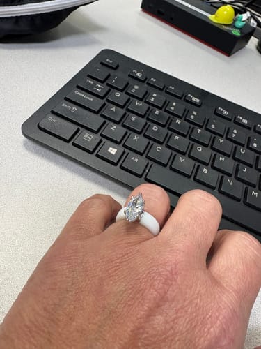 Customer wearing the white Silicone Ring with a marquise-cut stone on their hand over a black keyboard.