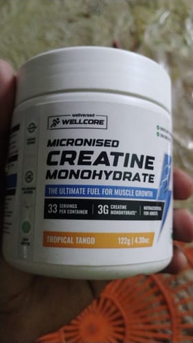 Reviewer holding a white tub of Wellcore Micronised Creatine Monohydrate in Tropical Tango flavor.