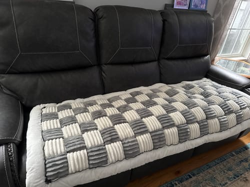 Customer's gray and white checkered furniture protector shown on a dark leather sofa.