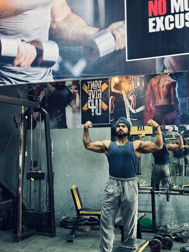 Customer flexing both biceps in a gym, showing muscle gain from using Wellcore Creatine.
