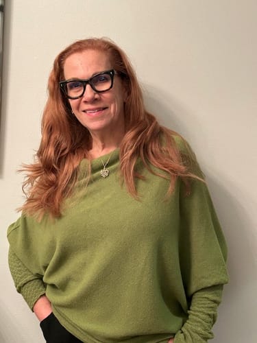 Reviewer smiling while wearing the olive green Asymmetric Draped seamless knit sweater.