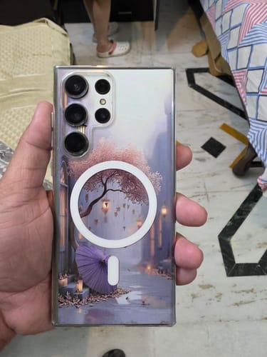 Customer holding a Galaxy S23 Ultra in the clear Magsafe case, featuring a purple scenic design and white magnetic ring.
