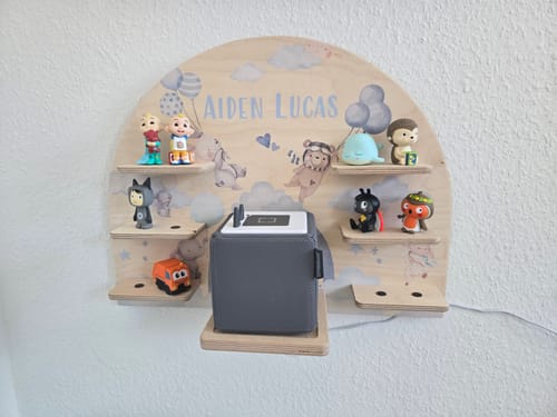 Kundenfoto: Das personalisierte Toniebox-Regal aus Holz an einer Wand, gefüllt mit einer Toniebox und Figuren.