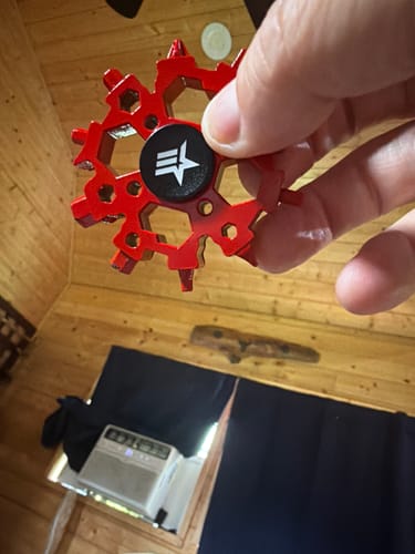 Customer holding the red, snowflake-shaped fidget spinner multitool.