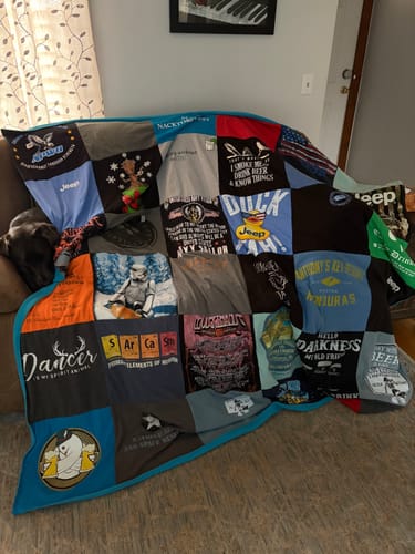 Customer's Project Repat T-Shirt Quilt made from many shirts, draped over a living room couch.