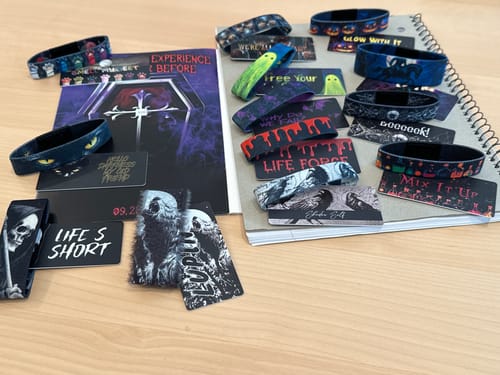 Customer's Coffin Collection of colorful Halloween-themed bracelets and cards laid out for display on a desk.