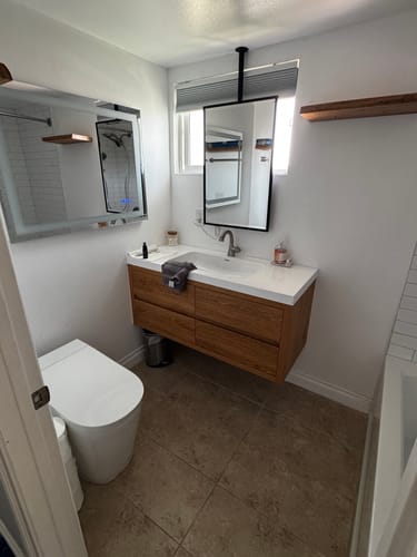 Customer's Saggia Floating Vanity with a light wood finish and white top, installed in a modern bathroom.