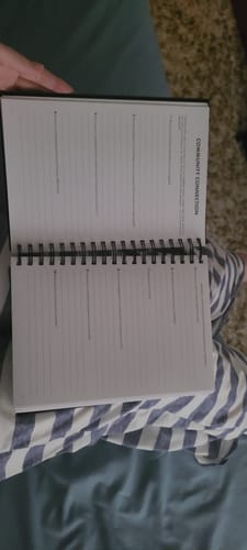 Customer holding the 2026 Dreambook + Planner open to the lined 'Community Connection' page.