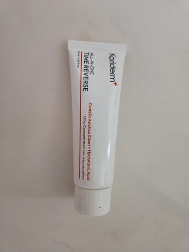 Reviewer's white tube of Koriderm All-In-One Time Reverse Cream on a flat surface.