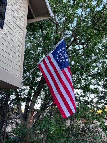 Customer's 1776 to 2026 Betsy Ross Flag flying from a flagpole on the side of a house.