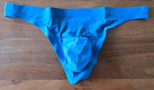 Customer's bright blue seamless thong laid flat on a wooden surface, showing the pouch design.