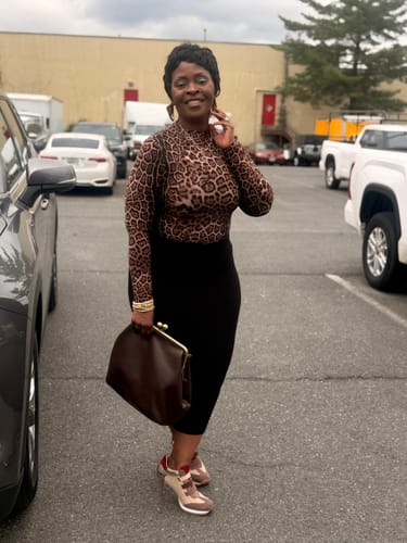 Reviewer standing outdoors in the long-sleeve Naked Print Bodysuit, styled with a black skirt.
