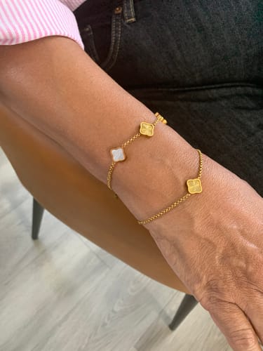 Customer's arm wearing a gold-tone chain bracelet with several clover-shaped charms.
