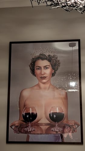 Customer's framed 'Majestic' art print of a topless queen figure hanging on an office wall.
